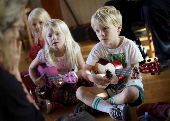 Children sitting and strumming the ukulele