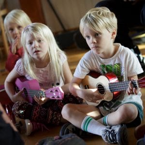 Children sitting and strumming the ukulele