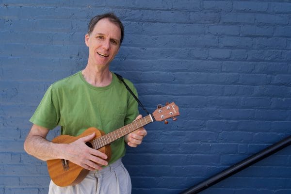 Man smiling holding a ukulele