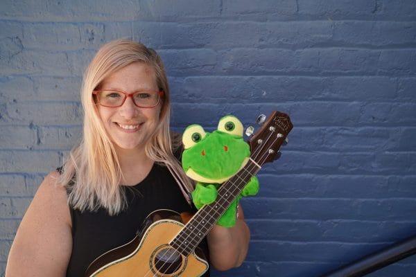 Woman smiling holding a ukulele and puppet