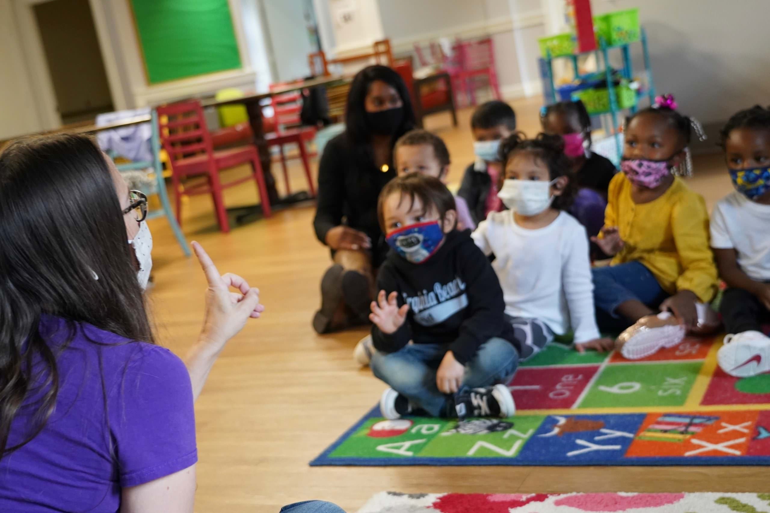 rootsandwingsemily Teacher Emily Ellis sitting with 7 young children during a music lesson.